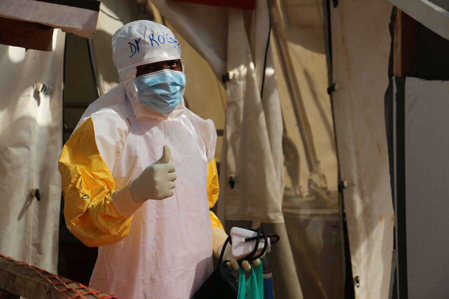 An Ebola health worker and survivor of the virus wearing full personal protective equipment (PPE) stands in an Ebola isolation ward in eastern DRC in this 2019 photo, raising a thumbs up. Photo: WFP/Jacques David