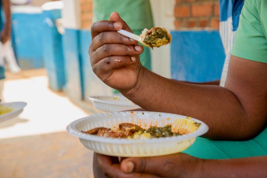 A closeup of a plate of food, with the hand of someone eating it. Photo: WFP/Arete/Seros Muyisa