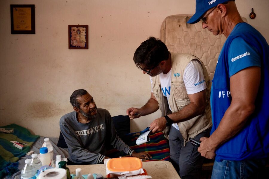 Three men - two wearing WFP T-shirts and vests - discuss in an office. Photo: WFP/Gustavo Vera