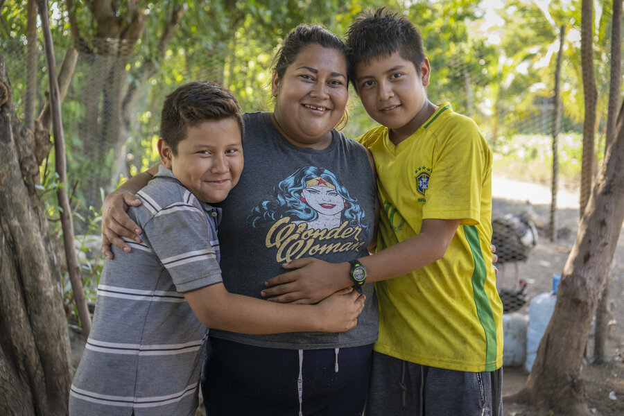 Jocelyn abrazada con sus dos hijos mirando a cámara.