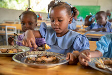 Una estudiante de primaria disfruta de una comida caliente preparada con alimentos producidos por agricultores locales. Foto: WFP/Theresa Piorr
