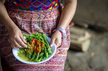 Mujer guatemalteca sostiene alimentos que serán compartidos en la mesa con su familia