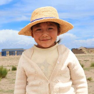 Niña uru parada frente a un acueducto