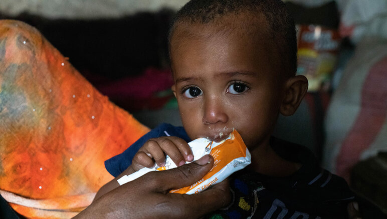 Yemen. La madre de Sultán le da de comer una pasta de maní nutritiva en casa. Él padece desnutrición aguda moderada. Gracias a los alimentos complementarios que recibe del WFP, Sultán ha comenzado a aumentar de peso y tiene más energía que antes. Pero todavía necesita tratamiento. Su familia también recibe asistencia alimentaria del WFP: harina, frijoles secos, aceite, azúcar y sal. WFP/Mohammed Awadh