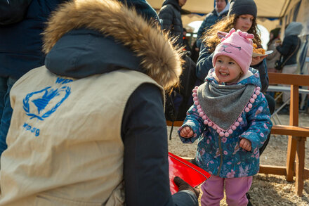 WFP staff from the back talks to a smiling kid at a distribution point
