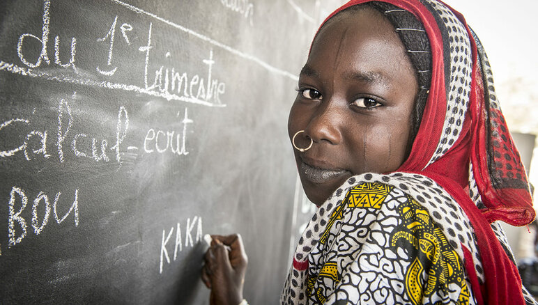 Kaka Marabou escribe su nombre en la pizarra de la escuela en Yakoua, Lago Chad. Los refugiados, las personas desplazadas y otras comunidades pobres de la cuenca del lago Chad dependen de la asistencia humanitaria para sobrevivir y el acceso a la educación básica también es limitado. WFP/Giulio d'Adamo